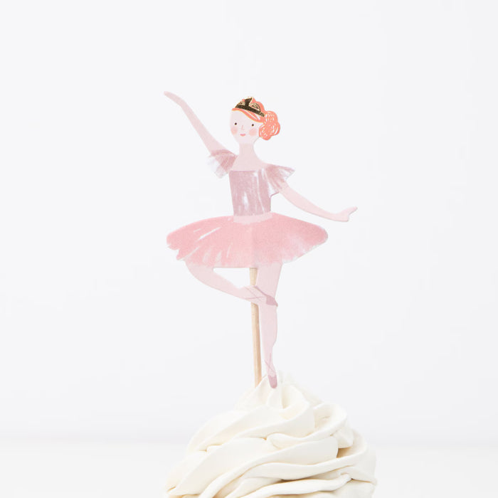 Ballerina cake topper on a white cake with a white background
