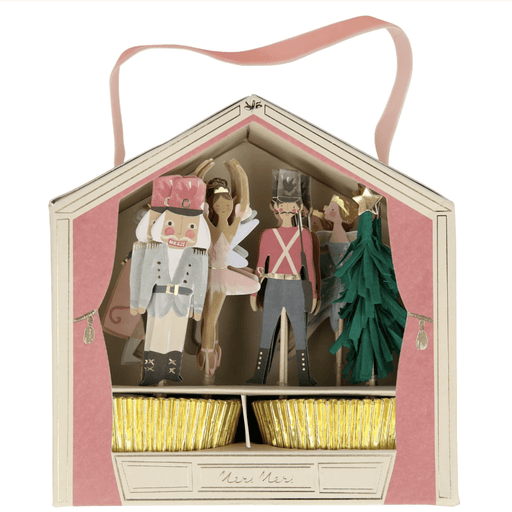 A Nutcracker Cupcake Kit displayed in an open box with various toppers and gold foil cupcake cases.