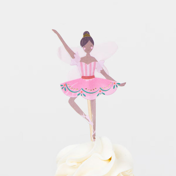 Ballerina cake topper on a white cake with a light pink background