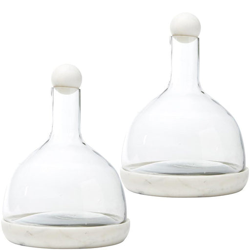 Two white marble and glass wine carafes with a clear glass body and white marble base, featuring a white marble stopper.