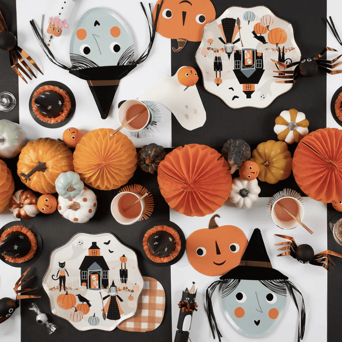 A die-cut paper plate designed to look like a witch's face with a black hat, copper foil detail, and black raffia hair.