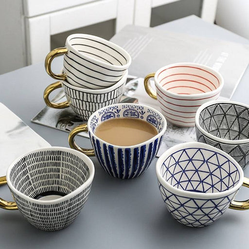 Collection of patterned ceramic cups and bowls on a light surface.