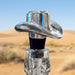 Clear glass bottle with cowboy hat-shaped cap on a decorative background