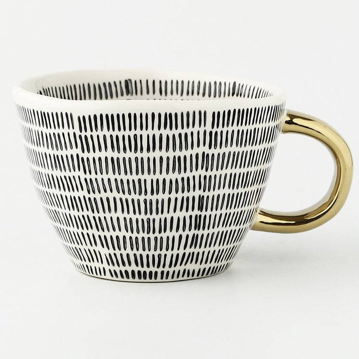 Mug with black wavy pattern and gold handle on a white background