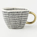 Mug with black wavy pattern and gold handle on a white background