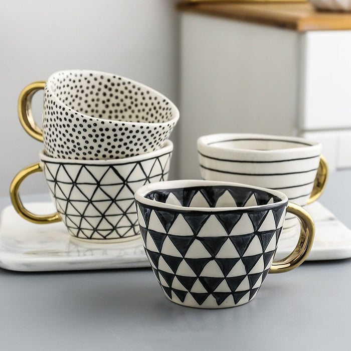 Set of patterned mugs with gold handles on a white surface