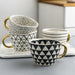 Set of patterned mugs with gold handles on a white surface
