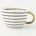 White mug with black stripes and a gold handle on a white background