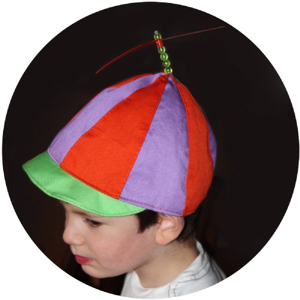 A child wearing a colorful Tweedledee hat with a propeller from Alice in Wonderland.