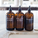 Three amber glass bottles with pump dispensers labeled 'liquid soap', 'hand soap', and 'lotion' on a marble surface.