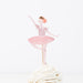 Ballerina cake topper on a white cake with a white background