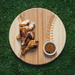 Wooden cutting board with roasted chicken pieces and a bowl of spices on grass