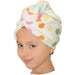 A child with a white hair turban with multicolored polka dots.