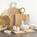 White ceramic turkey gravy boat with spoon and small turkey salt and pepper shakers — an elegant Thanksgiving table serving set styled with wooden cutting boards and woven accents