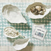 Decorative items including shells, a box with a bow, and a card on a polka dot placemat.