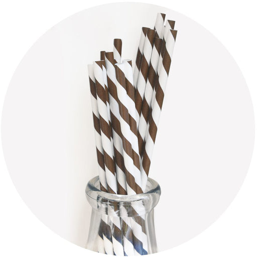A collection of chocolate brown and white striped paper straws displayed upright in a clear glass.