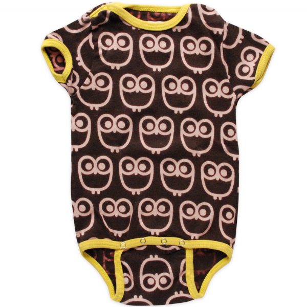 A selection of colorful onesies hanging on a wooden fence, each with a different pattern: one has blue waves, another is pink with hearts, and the last one is yellow with circles.