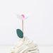 Decorative flower on a cupcake with white frosting against a white background