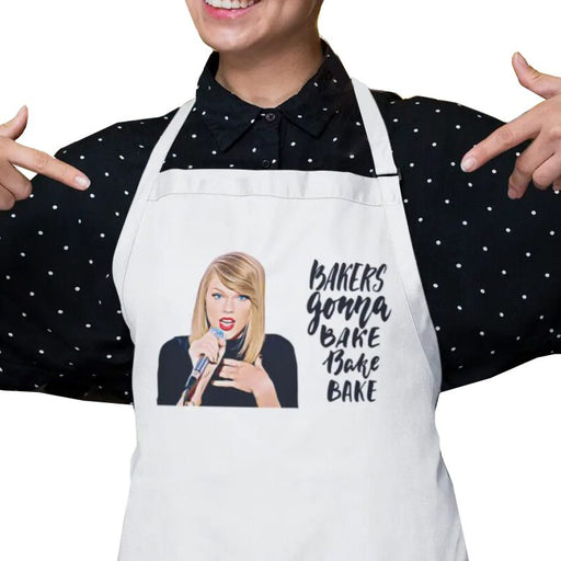 White apron featuring Taylor Swift face with the text 'Bakers Gonna Bake' and an image of a blonde woman holding a microphone