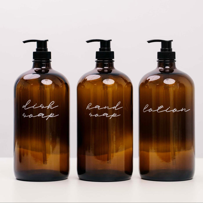 Three amber glass bottles labeled 'dish soap', 'hand soap', and 'lotion' on a white background.