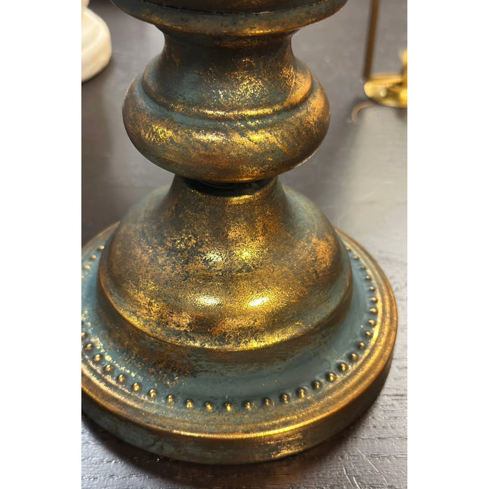 Close-up of a decorative vase with gold and blue finish on a gray surface.