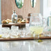 Modern Margarita glasses and pitcher on a table with snacks and bottles in the background