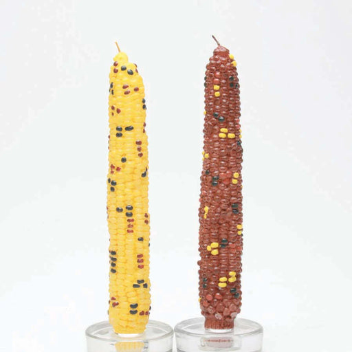 Two corn-shaped candles, one yellow and one brown, on a white background