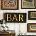 Decorative wall with framed pictures and a gold 'BAR' sign.