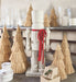 Decorative wicker nutcracker with straw Christmas trees and candles on a shelf.