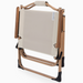 A folding outdoor lounge chair with a beige canvas seat and backrest, supported by a light brown wooden frame with black plastic feet, shown on a white background.