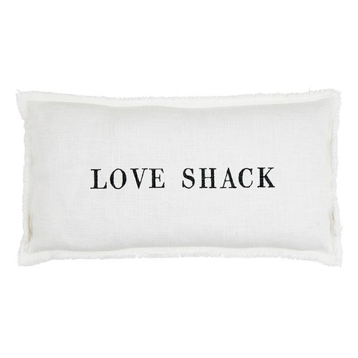 White lumbar pillowcase with the words “Love Shack” in black lettering styled on a neutral chair