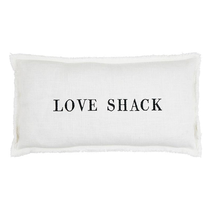 White lumbar pillowcase with the words “Love Shack” in black lettering styled on a neutral chair