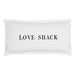 White lumbar pillowcase with the words “Love Shack” in black lettering styled on a neutral chair