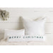 White pillows with 'Merry Christmas' text on a white wooden background
