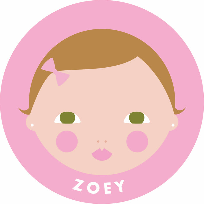 A stylized cartoon baby face illustration inside a pink circle, with the name 'ZOEY' printed at the bottom. The face has light peach skin, brown hair, green eyes, pink cheeks, and a small pink bow.
