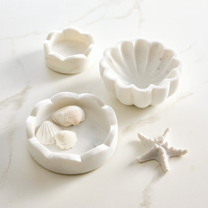 Set of white marble scallop shell-shaped bowls with seashells on a light background