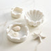Set of white marble scallop shell-shaped bowls with seashells on a light background