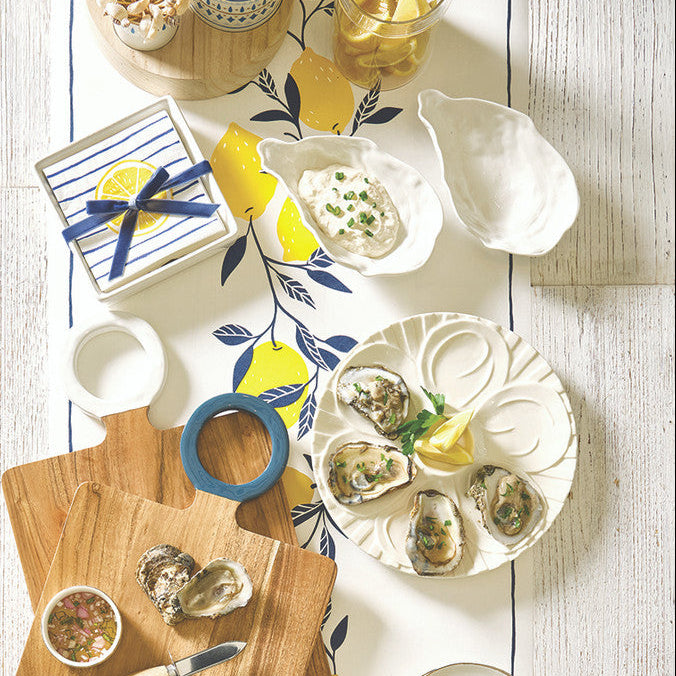 Table setting with decorative plates, bowls, and a cutting board on a light wooden surface.