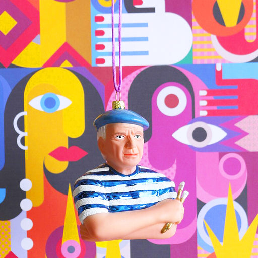 Pablo Picasso with a blue beret against his art