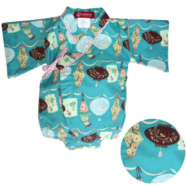 A woven kimono onesie for babies with a geometric pattern in shades of blue and beige, featuring kimono sleeves and a bow tie at the collar.
