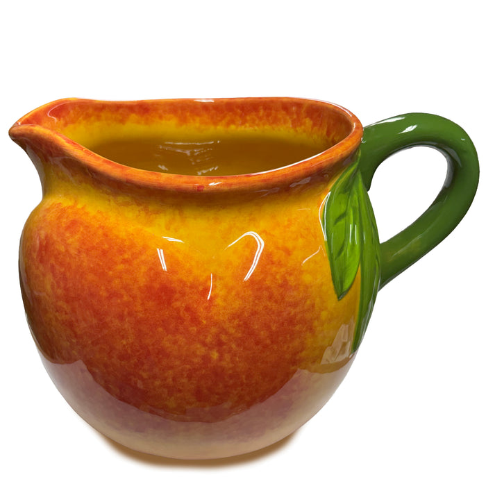 Ceramic pitcher with orange and green design on a white background