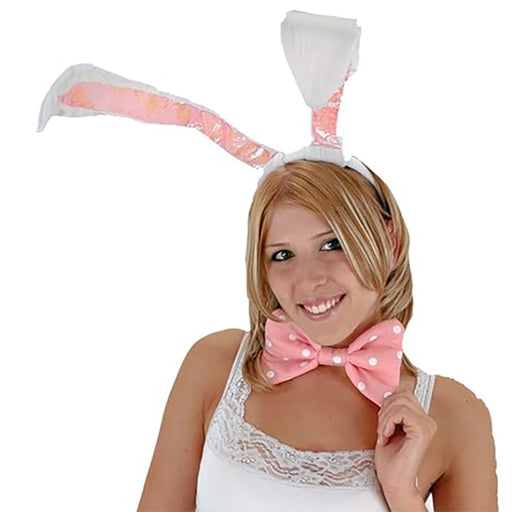 Woman wearing bunny ears and a pink bow tie on a white background