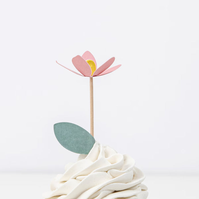 Pink flower cupcake topper on a white cake with a white background