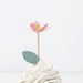 Pink flower cupcake topper on a white cake with a white background
