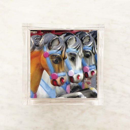 Paper napkin featuring a close-up of colorful carousel horses lined up in a row with vibrant harness details