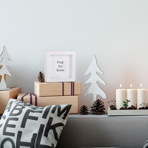 Decorative setup with candles, pinecones, and a framed 'pray for Snow' quote