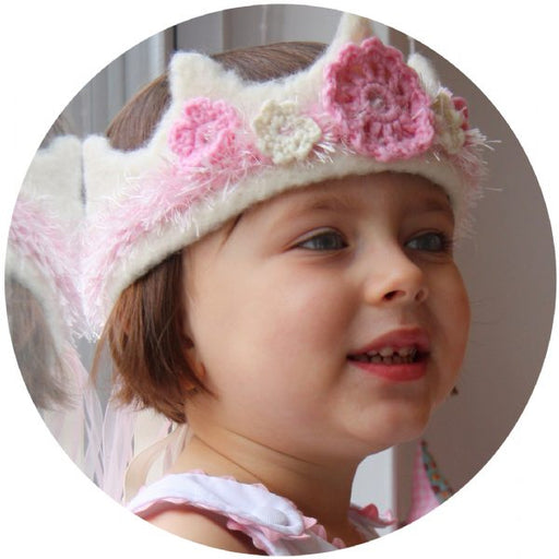 A young child wearing a pink and white crochet wool crown with flower details.