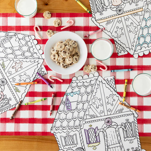 Coloring books, cookies, and milk on a red and white checkered tablecloth.