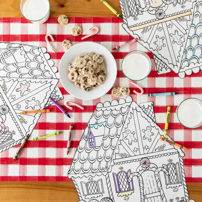 Coloring books, cookies, and milk on a red and white checkered tablecloth.