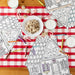 Coloring books, cookies, and milk on a red and white checkered tablecloth.